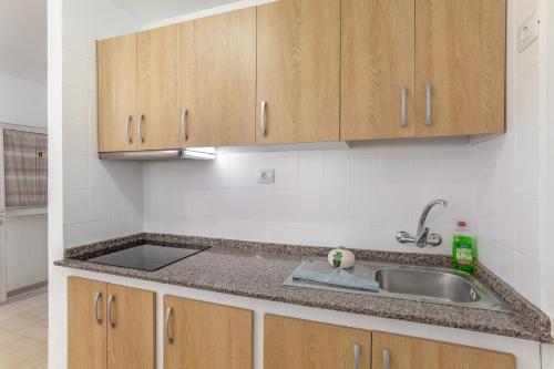 a kitchen with a sink and wooden cabinets at Apartamento Danoe 4 in Mogán