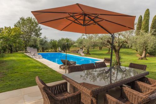a table with an umbrella next to a swimming pool at Villa Minerva in Lazise