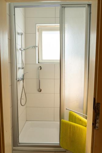 a bathroom with a shower with a yellow towel at Knollgut Ferienwohnung Buchberg in Goldegg
