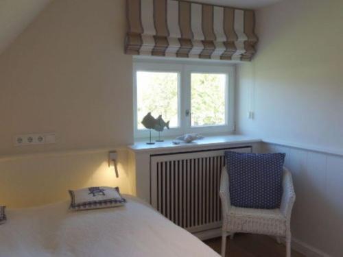 a bedroom with a bed and a window and a chair at Sylthus-Haithabu in Wenningstedt