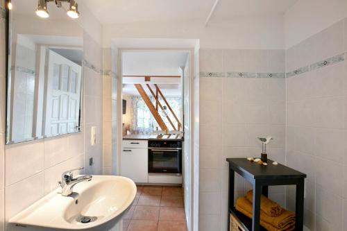 a white bathroom with a sink and a kitchen at Ferienhäuschen am See in Bestensee
