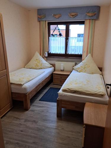 two beds in a small room with a window at Pension Andrea in Herbstein