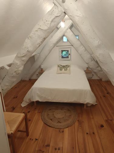 a bedroom with a white bed and a wooden floor at Mas De Palaille, Piscine et Nature in Salvagnac-Cajarc