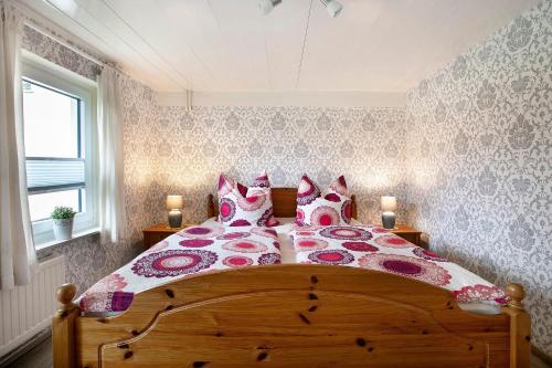 a bedroom with a large bed with red and pink pillows at Ferienhaus Bruhn in Flensburg