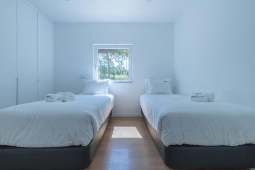 two beds in a room with white walls and a window at Forest Village T2 in Mindel