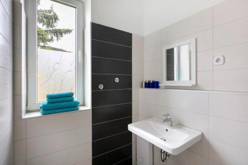 a white bathroom with a sink and a window at Haus Meistereck Melzow in Melzow