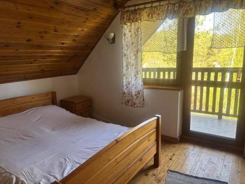 a bedroom with a bed and a large window at Domek wakacyjny in Krzywólka