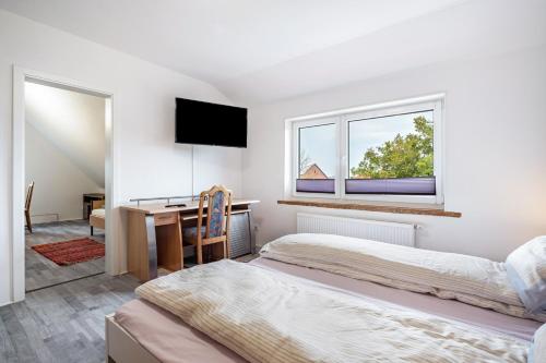 a bedroom with two beds and a desk and a window at Ferienwohnung Dierking in Gilten