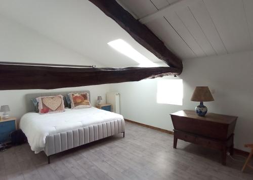 a bedroom with a white bed and a table at Chambres d' hotes Terre Happy in Ribérac