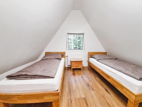 two beds in a attic bedroom with a window at Ferienhaus 88 in Bad Arolsen