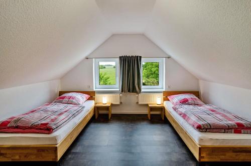 two beds in a attic room with two windows at Seehund in Stedesdorf