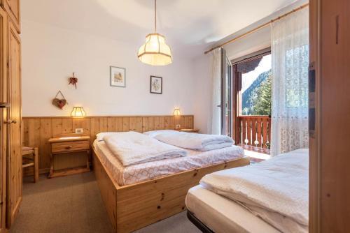 two beds in a bedroom with a window at Casa Lorenz 3 in Canazei