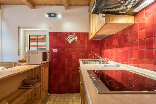 a kitchen with a sink and red tiles on the wall at Casa Lorenz 3 in Canazei