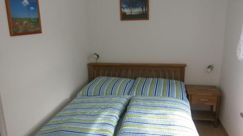 a bed with a striped pillow and a night stand at Seeblick Ferienbungalow in Leezen