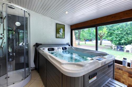a large tub in a bathroom with a window at Villa Rodolphe in Le Pian-Médoc