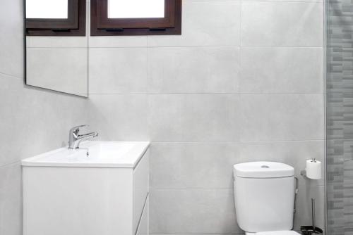 a white bathroom with a toilet and a sink at Villa Soleva in Conil de la Frontera