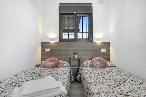 a room with two beds with pillows and a window at Villa Soleva in Conil de la Frontera
