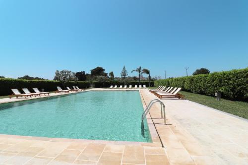 a large swimming pool with lounge chairs and trees at Casa Vacanza Monte Pulciano Otranto in Otranto