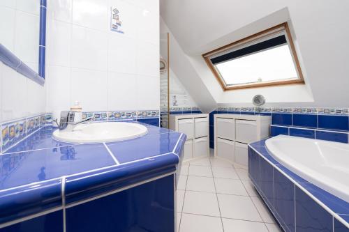 a blue and white bathroom with a tub and a sink at Maison Ker Galeret in Sarzeau
