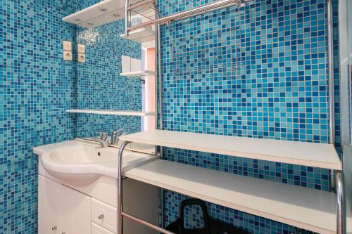a blue tiled bathroom with a sink and a mirror at Maison Plouha proche plage in Plouha