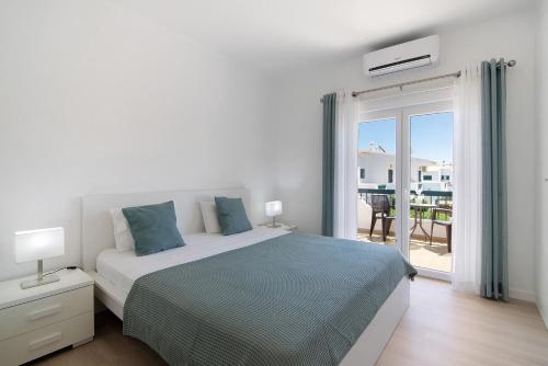 a white bedroom with a bed and a balcony at Villa Janeca in Albufeira
