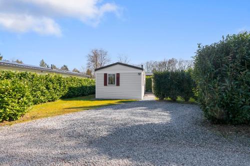 a small white shed on the side of a driveway at Knus chalet in de bossen van Epe met fietsen in Epe