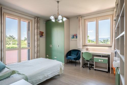 a bedroom with a bed and a desk and windows at Villa Angela in Capannori