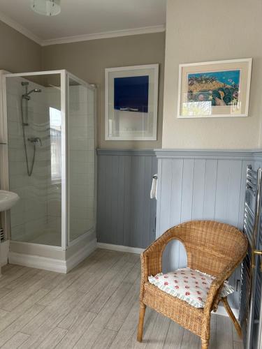 a bathroom with a shower and a wicker chair at Gyves House in Eastbourne