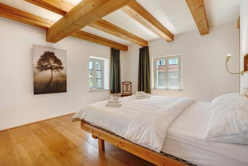 a bedroom with a large white bed and two windows at Ferienhaus im Vorwerk Nickern in Dresden