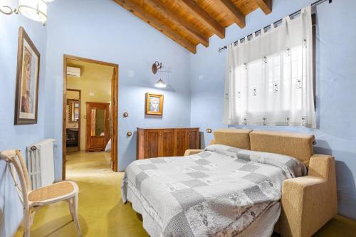 a bedroom with a bed and a chair and a window at La Carrasca - Naranja in Catral