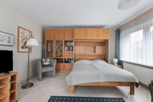 a bedroom with a bed and a chair and a television at Haus Gartenidylle in Wesselburen