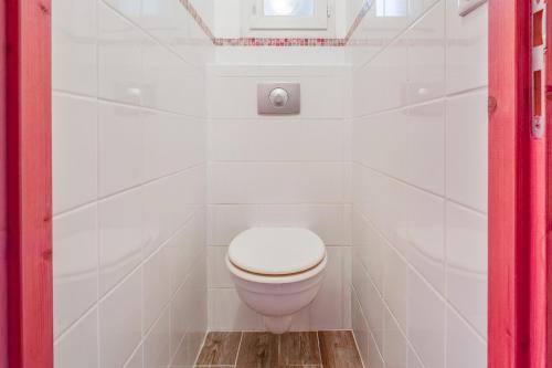 a white toilet in a white tiled bathroom at Chambre Laurier Rose in Piolenc