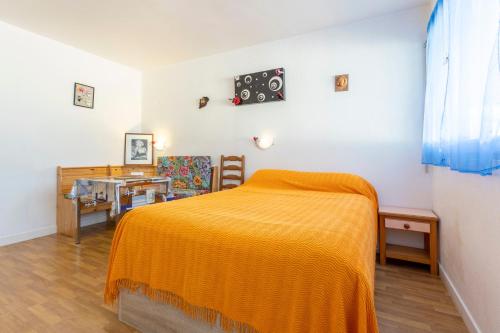 a bedroom with a bed with an orange blanket at Studio Turquoise à 100m de la plage in Bénodet