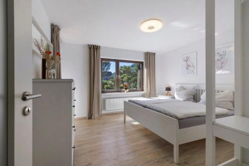 a white bedroom with a bed and a window at Ferienwohnung Mayer in Albstadt