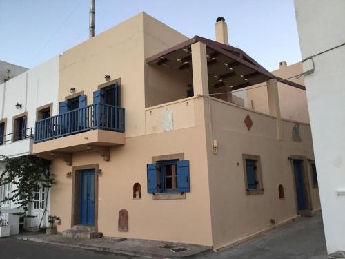 a building with blue windows and a balcony at Emma's maisonette house by Kapsali beach in Kapsali