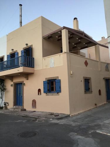 a building with blue windows and a balcony at Emma's maisonette house by Kapsali beach in Kapsali