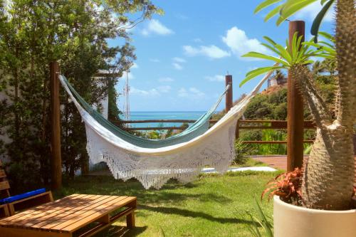 a hammock in a garden with a view of the ocean at Casa Edom - Maceió in Maceió
