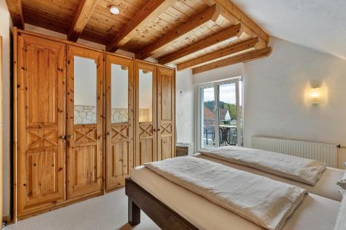 a bedroom with a bed with wooden cabinets and a window at Ferienwohnung Heilsbergblick in Hilzingen
