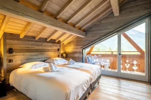 sypialnia z dwoma łóżkami i dużym oknem w obiekcie Chalet Camillou w mieście Champagny-en-Vanoise
