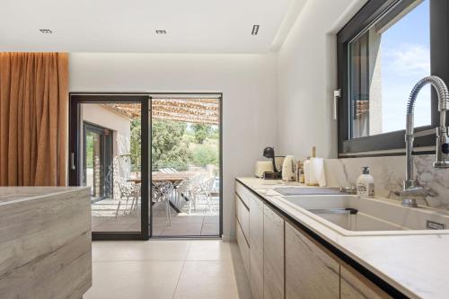 a kitchen with a sink and a view of a patio at Villa Belenos Piscine vue mer in Roquebrune-sur-Argens