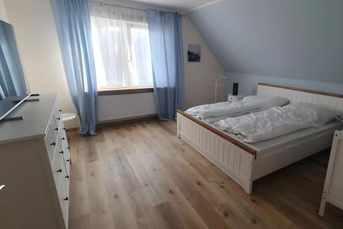 ein Schlafzimmer mit einem Bett und einem Fenster mit blauen Vorhängen in der Unterkunft Bei Heike in Zetel