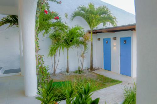 a building with blue doors and palm trees at Casa Edom - Maceió in Maceió