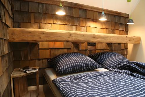 a bedroom with a wooden wall with a bed and two pillows at Ferienwohnungen beim Weilerbauer in Gerstetten