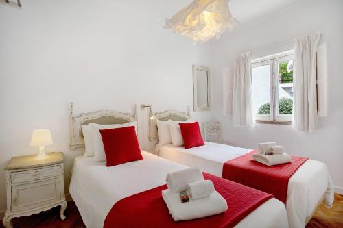a bedroom with two beds with red and white sheets at Páteo da Várzea 4 in Colares