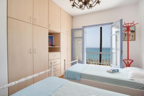 a bedroom with two beds and a window with the ocean at Orkos View House in Naxos Chora