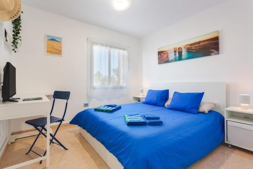 a bedroom with a blue bed and a desk at Oasis Duna_Sun Fun Pool in Corralejo