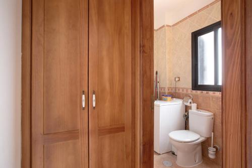 a bathroom with a toilet and a wooden cabinet at Casa Nanda in Fasnia