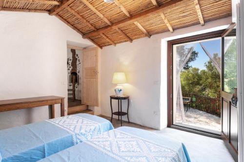 a bedroom with two beds and a large window at Casa vacanza Stazzu Saiacciu in Palau