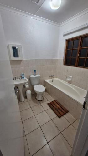a bathroom with a tub and a toilet and a sink at Pendleberry Unit 85 in Warmbaths