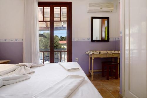 a bedroom with a bed and a mirror and a window at Areti Orfeas Apartment 7 in Vasilikos